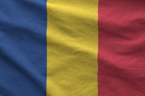 Romania flag depicted on folded wavy fabric of old cloth
